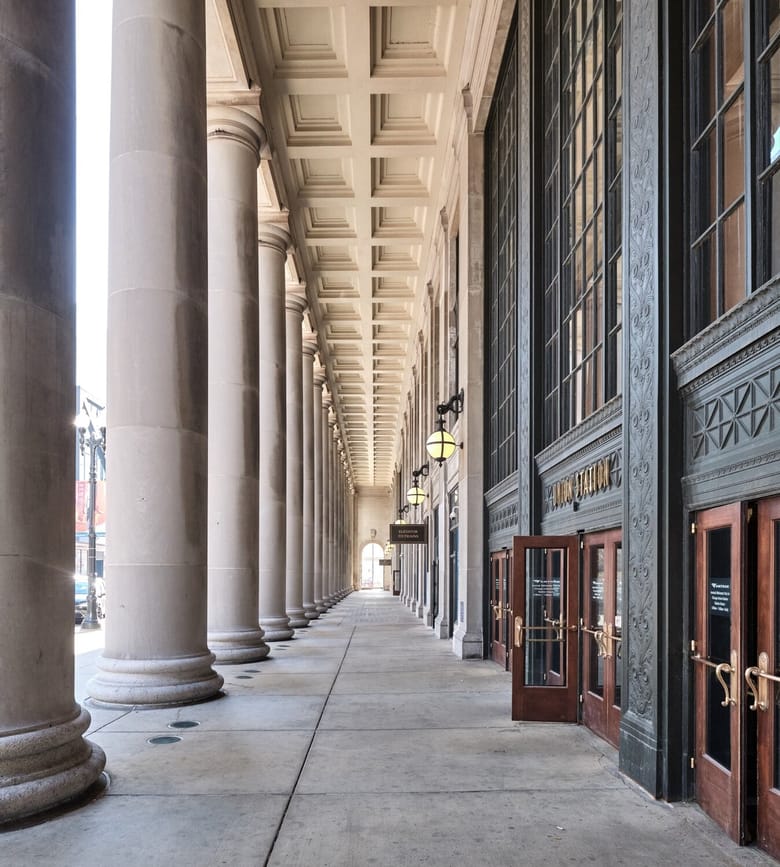 Exterior shot of Union station featuring the wooden doors surrounded by ornate green walls on the left and large white columns to the right