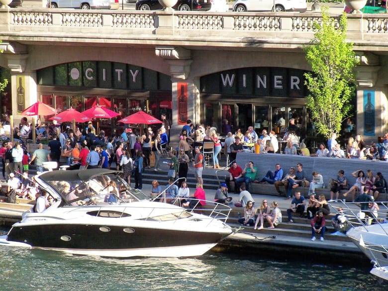 Many people sitting outside with boats in front of them. 
