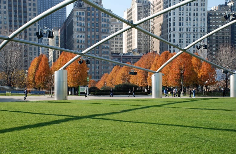 Large metal sloped structure sits on green grass with skyscrapers in the background