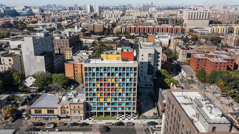 Aerial image of a ten story builing with bright colors on each balcony including red, yellow, blue, and green.