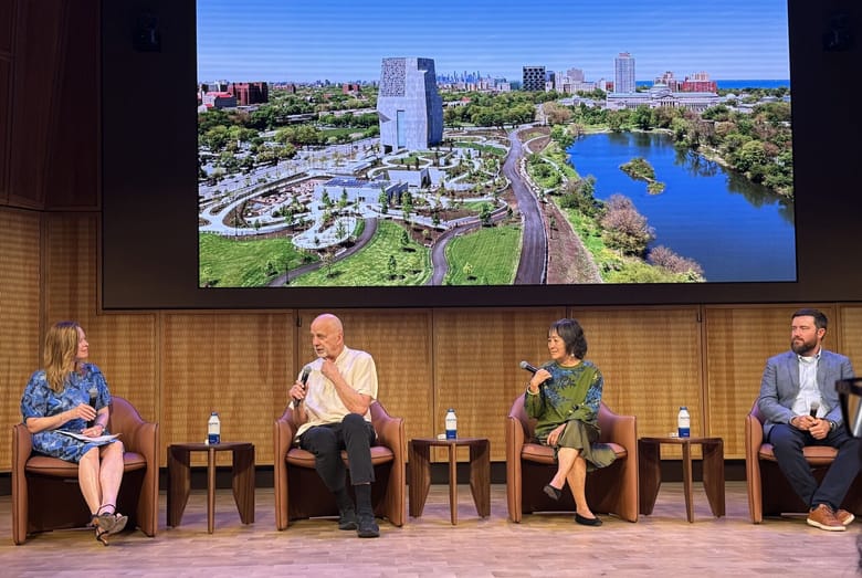 A panel of people talking in front of a large screen.