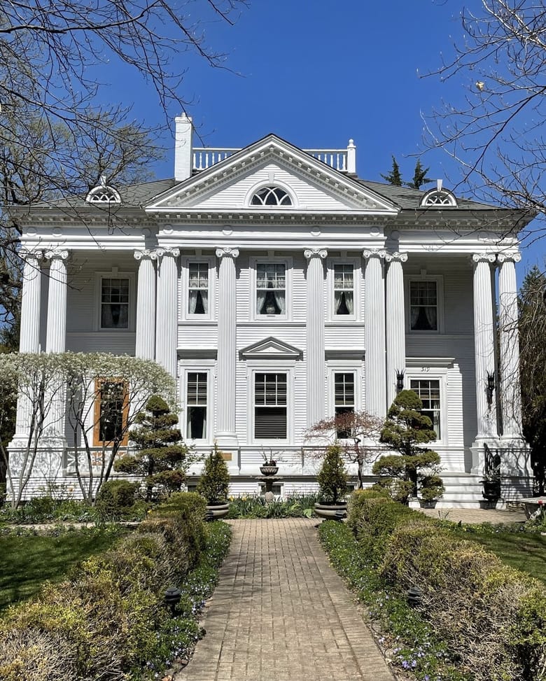 Big white house with garden in front.