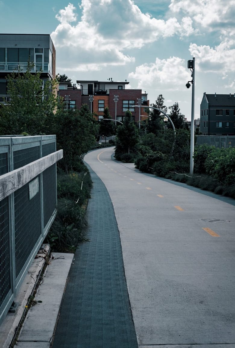 Unpopulated elevated bike path with residential buildings in background.