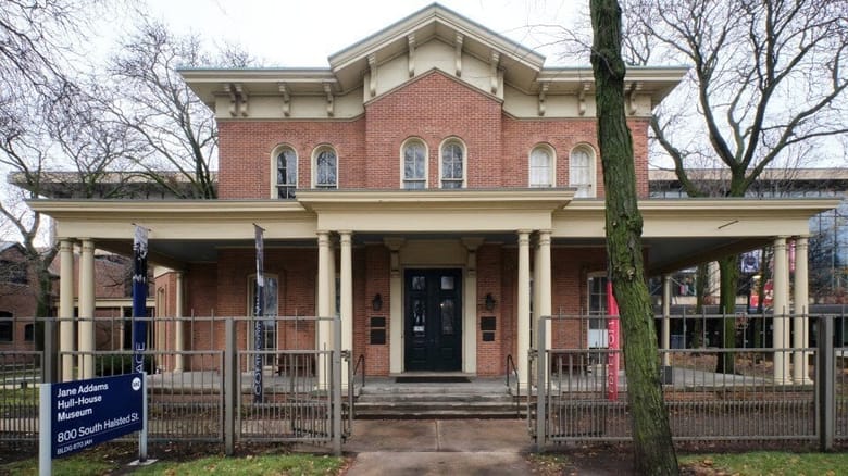 Large two story residential red brick building with cream colored trim and a large front porch.