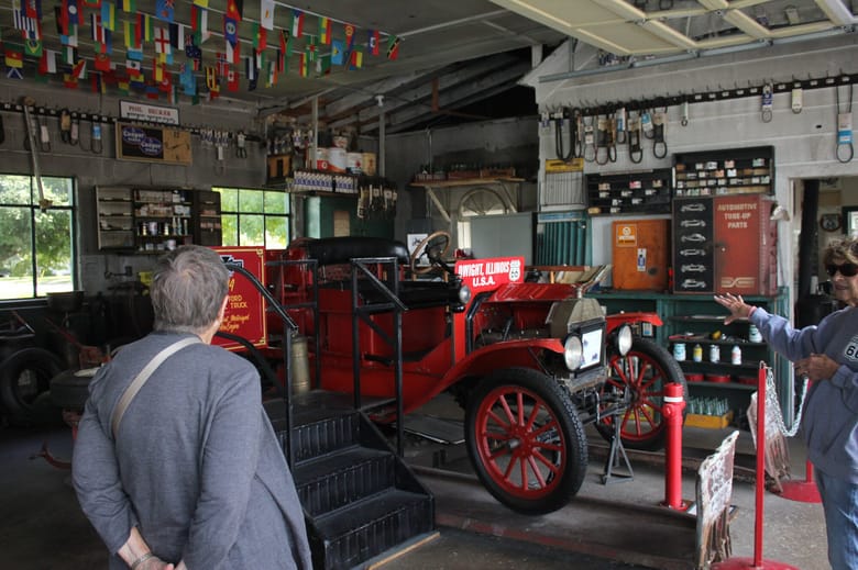 Two people looking at an old car in a garage.