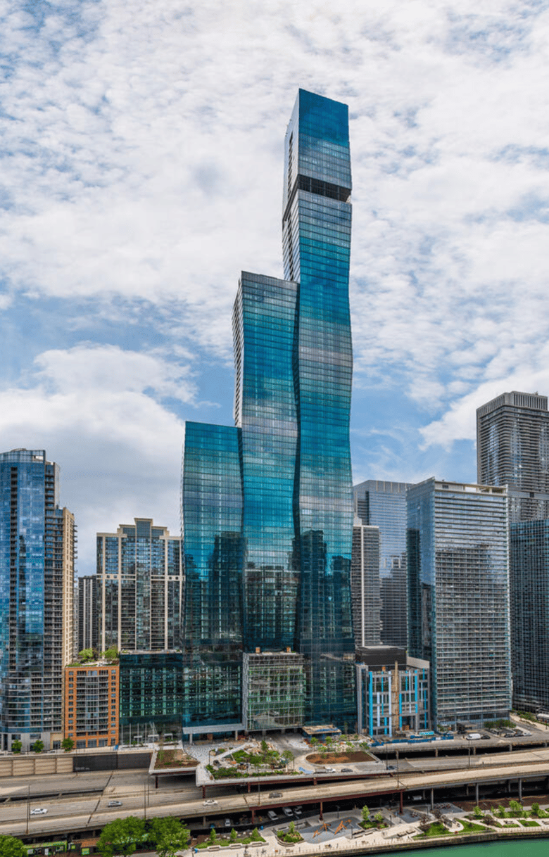 One building comprised of 3 glass towers, against cloudy sky.