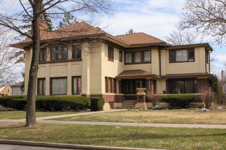 Image of a two story tan and brown bungalow style house.