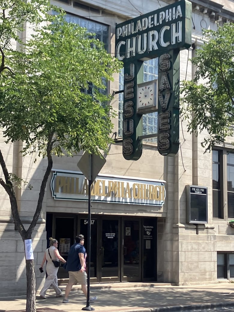 Outside of a church with a big sign.