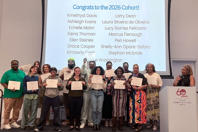A group of people in front of a large screen holding up certificates.