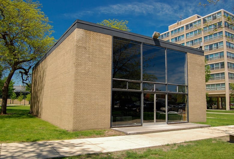Exterior perspective of a one-level box shaped building with glass doors in the center