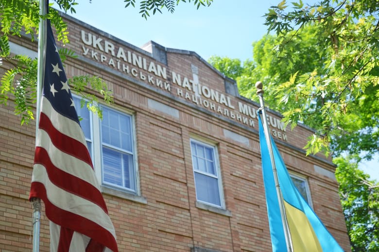 Red brick building with windows and flags in the foreground. 