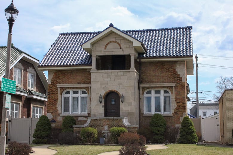 Image of a small red brick bungalow style house with blue tiled roof.