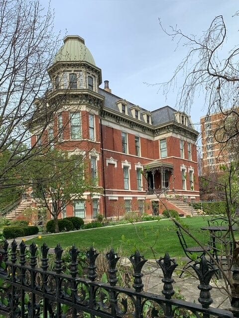 A red brick house with a large green lawn.