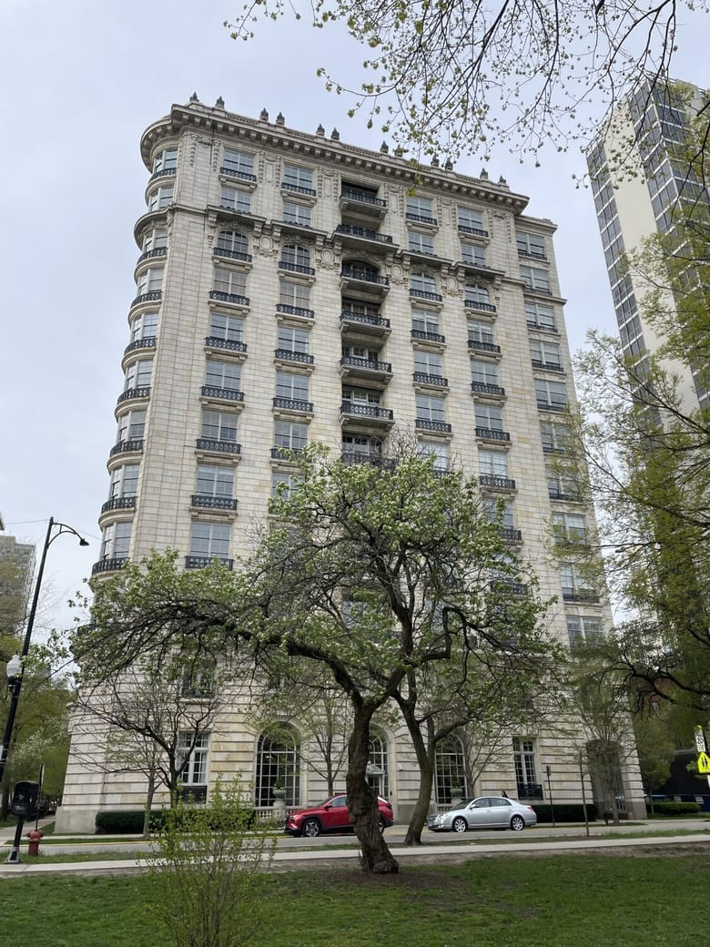 Tall white building with windows and balconies down the middle looking up form below.