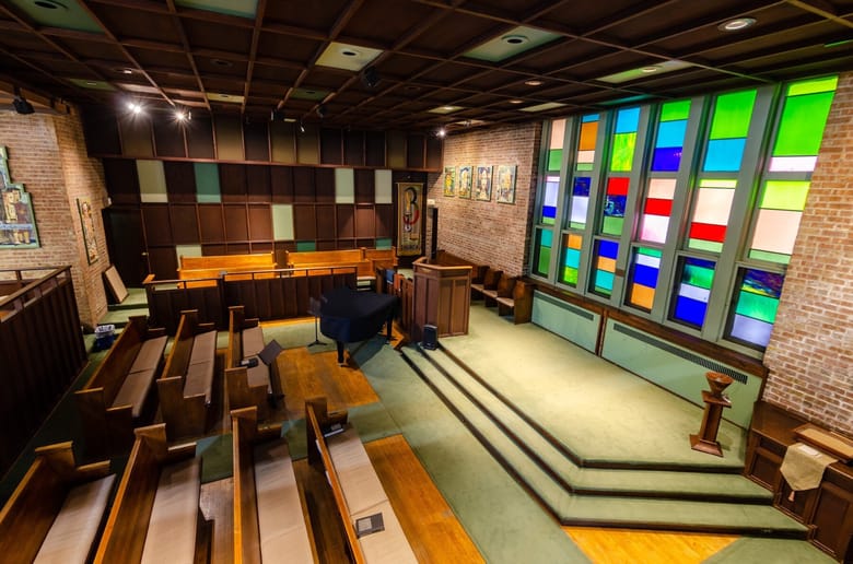 Interior of a church with green carpet and stained glass.