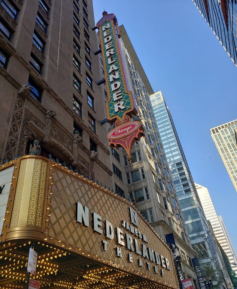 Exterior of a theater with two big signs.