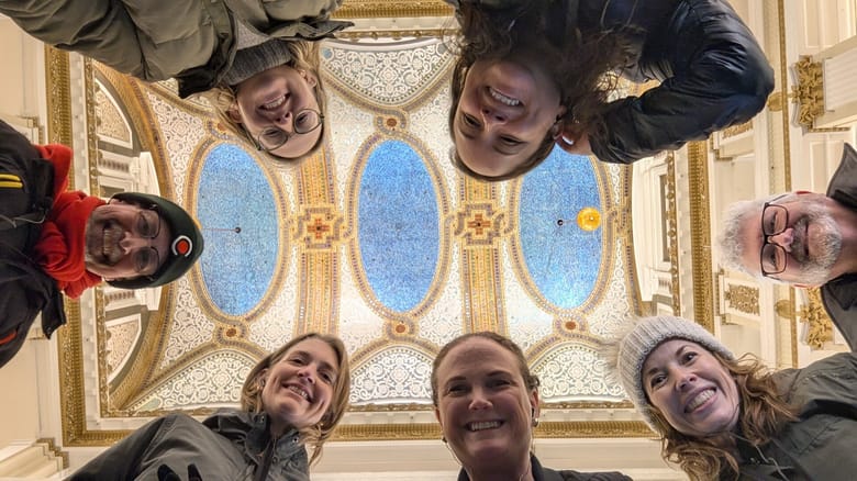 A group of people pose with the Tiffany glass ceiling at Macy's on State Street