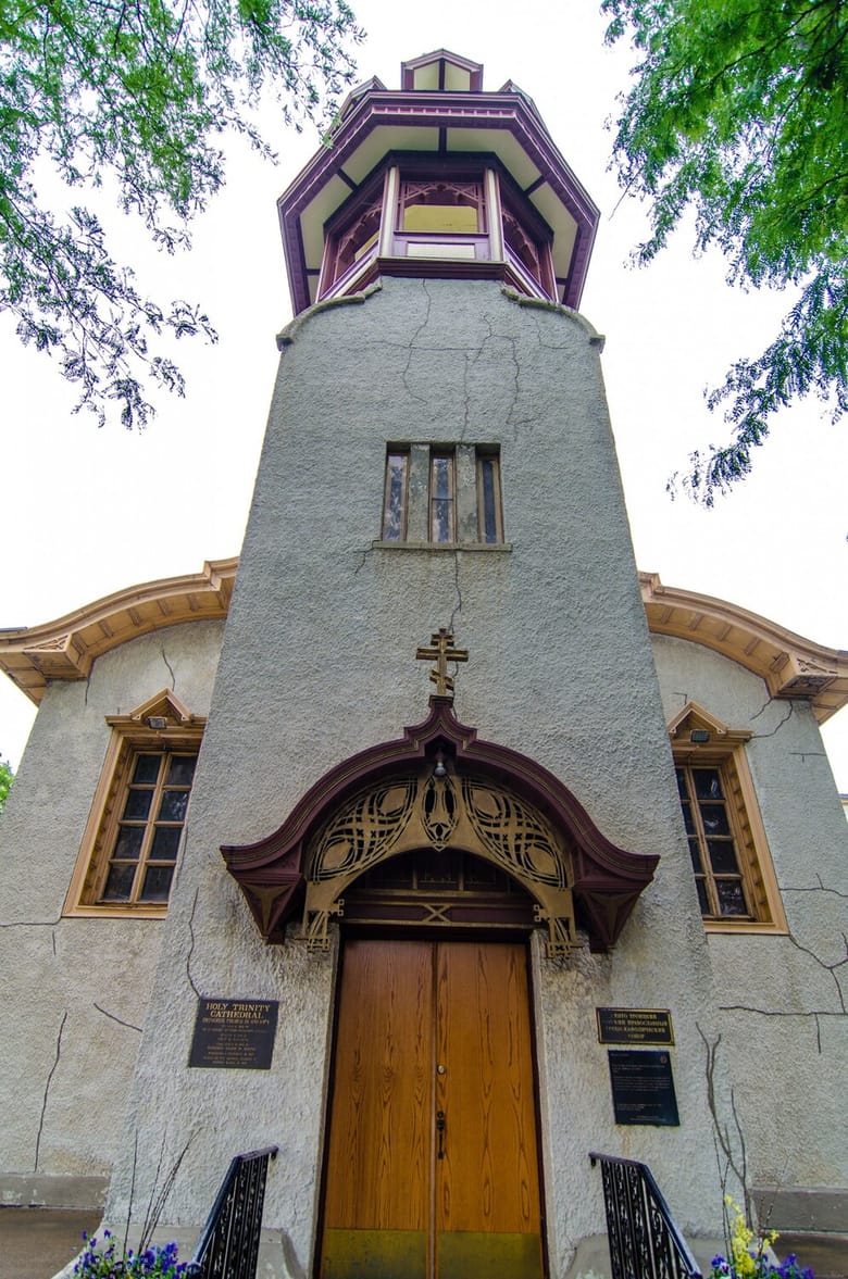Image of the front of a building with a tall tower, white exterior, and yellow trim. 