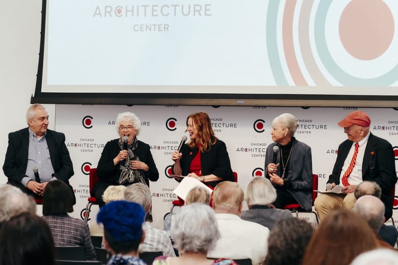 A panel of people talking in front of a large screen.