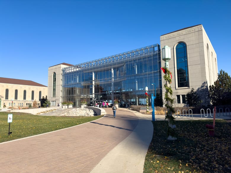 Large building with grey stone sides and a  glass facade. 