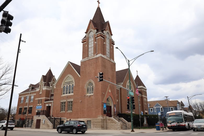 Exterior photo of a brick church with a big bell tower.