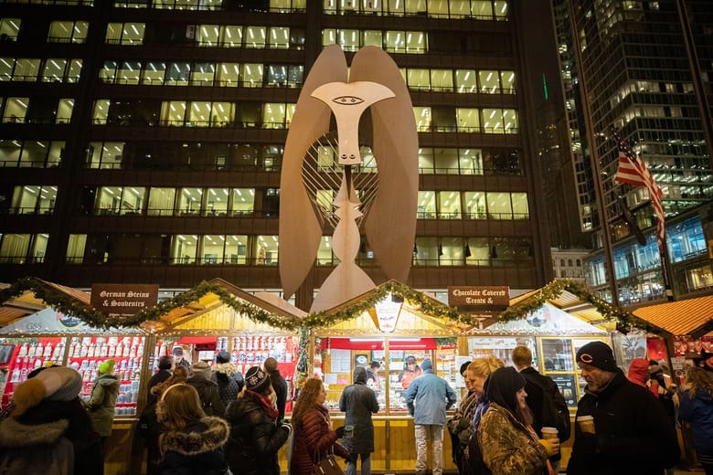 Holiday market with a large sculpture and people shopping in the foreground